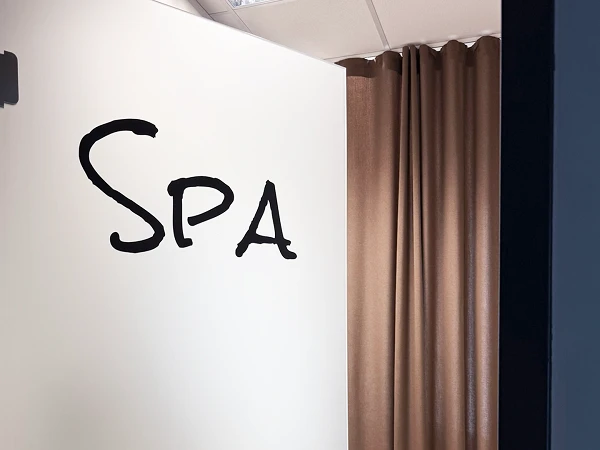 Die offene Tür eines Raumes mit der Aufschrift "Spa" zieht ins Innere, wo ein Vorhang in Braun hängt. An der Tür hängt ein Schild mit der Aufschrift "Bitte Nicht Stören".