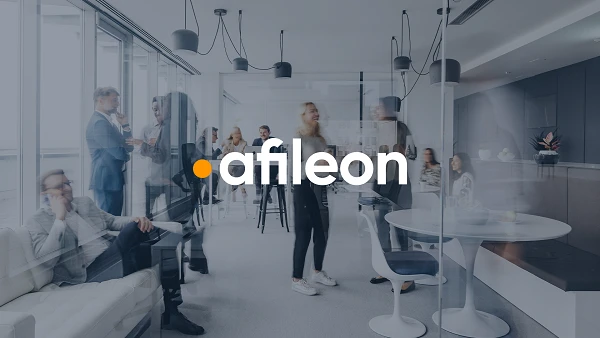 Ein modernes Bürointerieur mit mehreren Personen, die miteinander kommunizieren und arbeiten. In der Mitte des Bildes steht das Logo „afileon“ deutlich sichtbar.