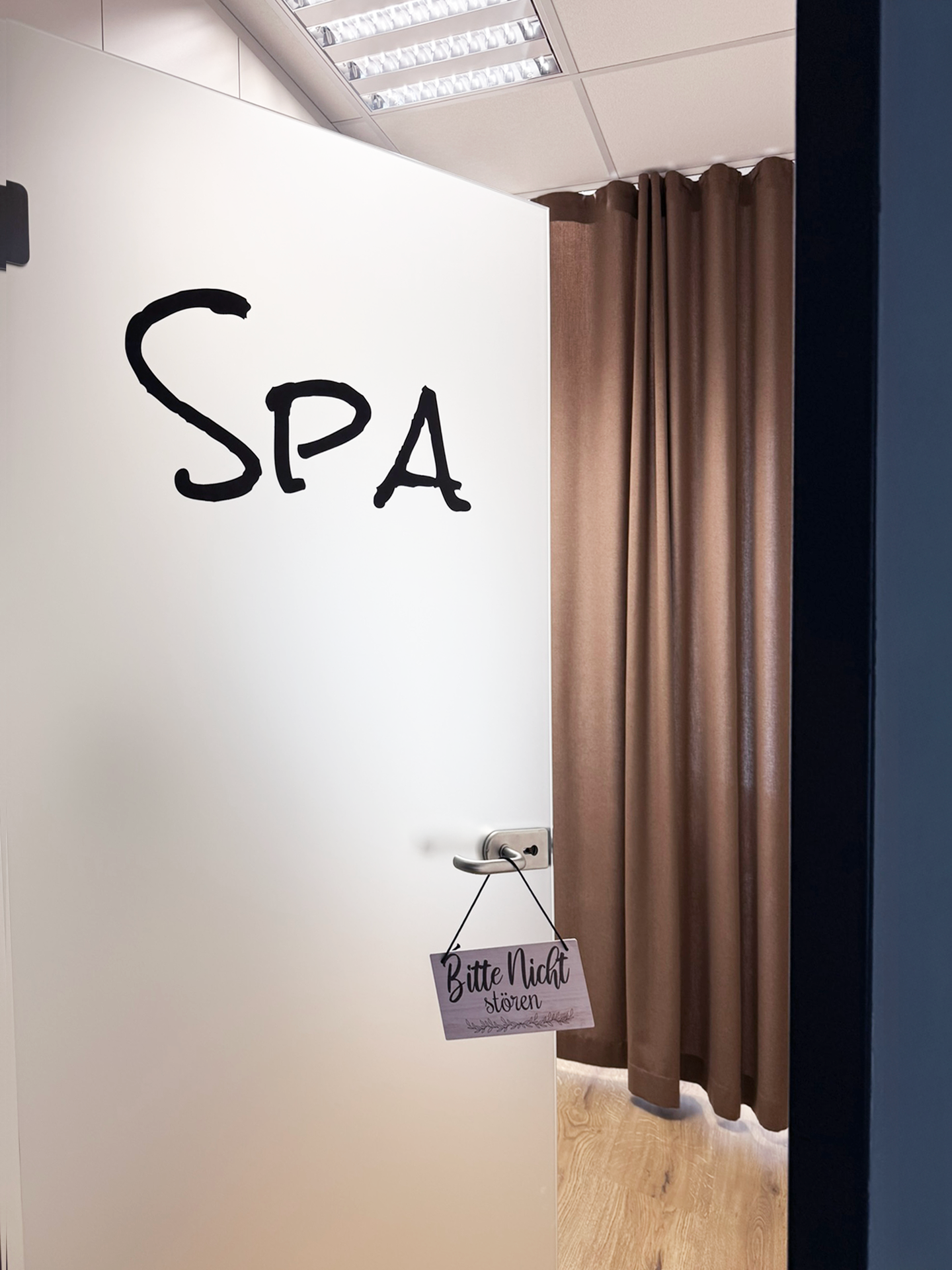 Die offene Tür eines Raumes mit der Aufschrift "Spa" zieht ins Innere, wo ein Vorhang in Braun hängt. An der Tür hängt ein Schild mit der Aufschrift "Bitte Nicht Stören".